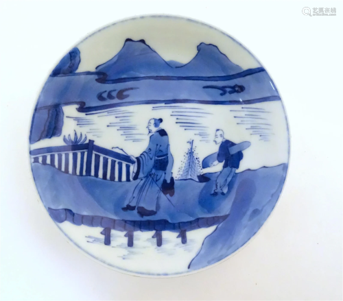 A Chinese blue and white dish with two figures crossing a br...