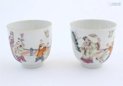 A pair of Chinese tea cups decorated with figures in a garde...