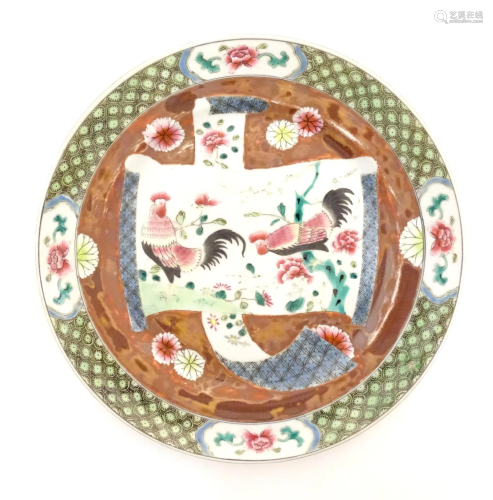 A Chinese plate decorated with a scrolling central panel dep...