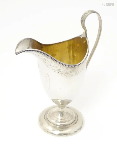 A Geo III silver helmet shaped cream jug with gilded interio...