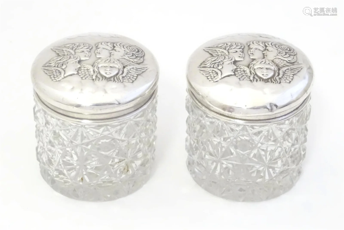 A pair of cut glass dressing table pots with embossed silver...