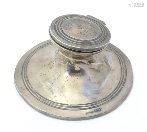 A silver inkwell of capstan form with glass liner and inscri...