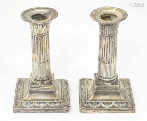 A pair of silver candlesticks with fluted columns on squared...