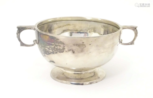 A silver porringer with twin handles and pedestal foot, hall...