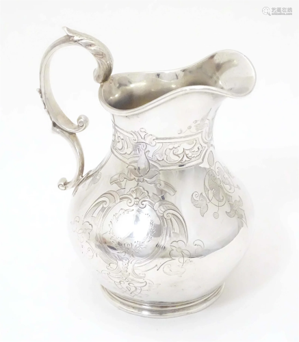 A Victorian silver cream jug with engraved decoration, hallm...