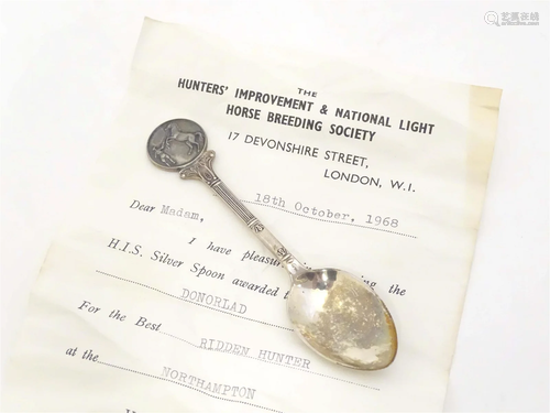 A silver trophy teaspoon, the handle decorated with image of...