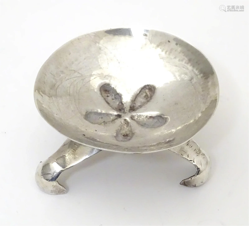 A white metal pin dish with floral detail to centre on three...