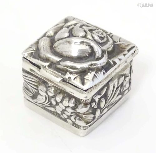 A silver pill box of squared form with floral decoration, ha...