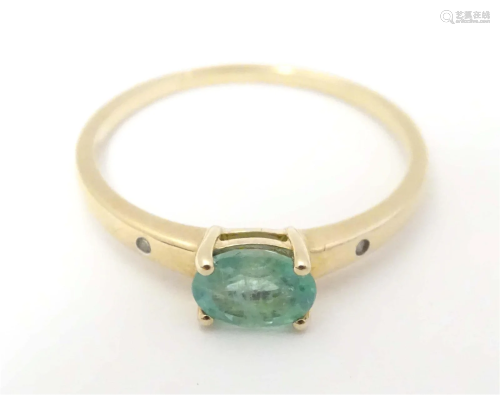 A 9ct gold ring set with oval green stone to centre flanked ...