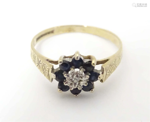 A 9ct gold ring set with central diamond bordered by blue sp...