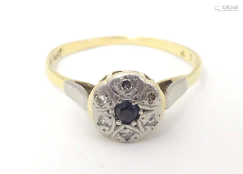 An 18ct gold ring set with central sapphire bordered by diam...