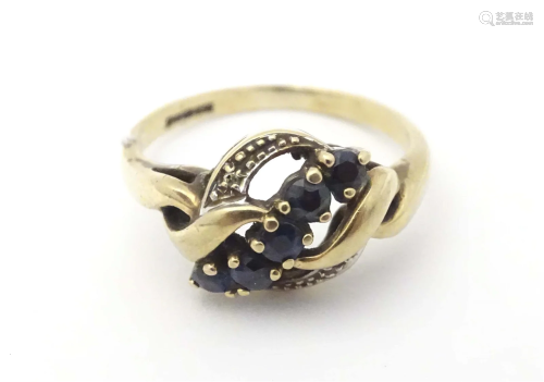 A 9ct gold ring set with banded blue spinel flanked by diamo...