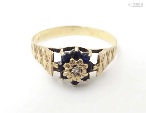 A 9ct gold ring set with central diamond bordered by spinels...