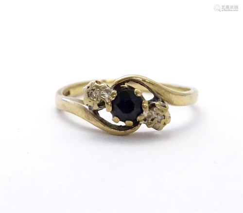 A 9ct gold ring set with central blue spinel flanked by diam...