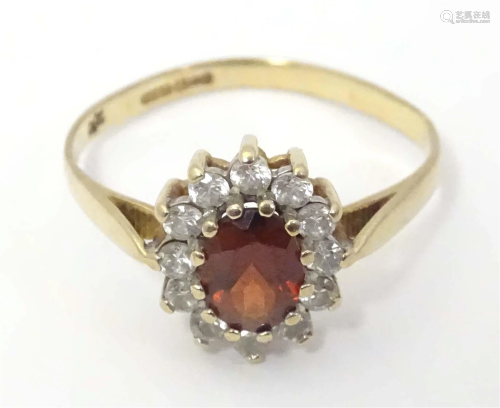 A 9ct gold ring set with central red tone bordered by white ...