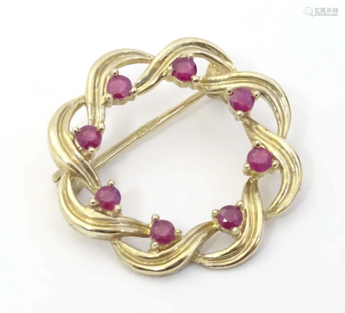 A 9ct gold brooch of circular form set with rubies. 1" ...