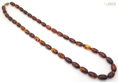 A vintage long bead necklace of graduated amber coloured bea...