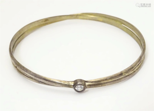 A silver bangle with white stone detail