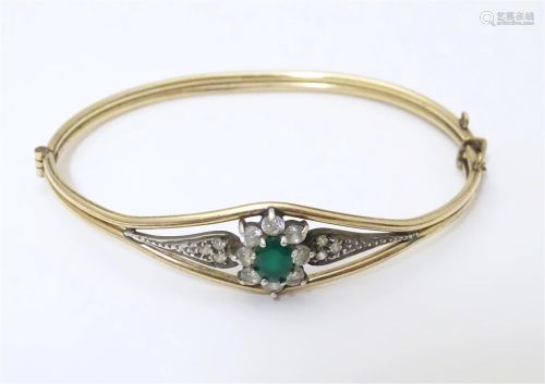 A 9ct gold plated bracelet of bangle form set with green and...