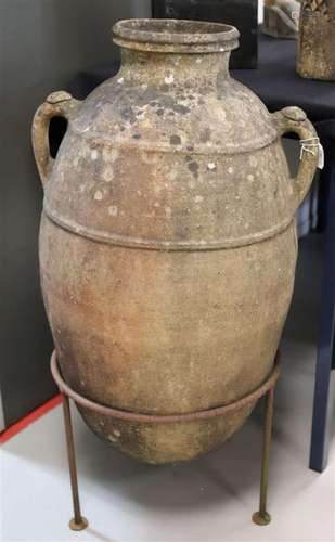 A terracotta amphora olive jug with handles in a wrought iro...