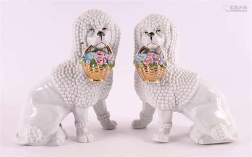 A pair of white porcelain sitting poodles with flower basket...