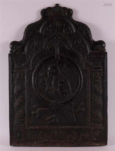 A cast iron fireback with an embossed image of a parrot in a...