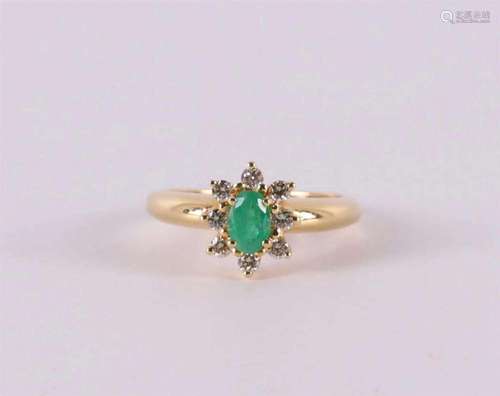 An 18 kt gold ring with an oval facet cut emerald and entour...