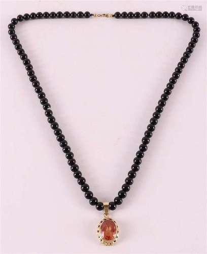 A black onix ball necklace with a 14 kt gold clasp and penda...