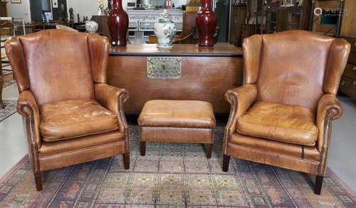 A pair of ear club armchairs with brown leather upholstery, ...