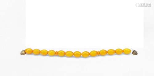 Bracelet composé de perles d'ambre jaune et terminé par ...