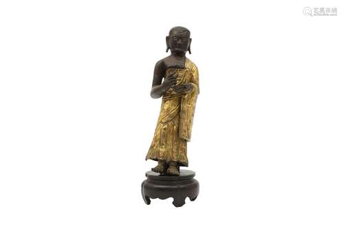 A CHINESE PARCEL-GILT COPPER ALLOY REPOUSÉE FIGURE OF A MONK...