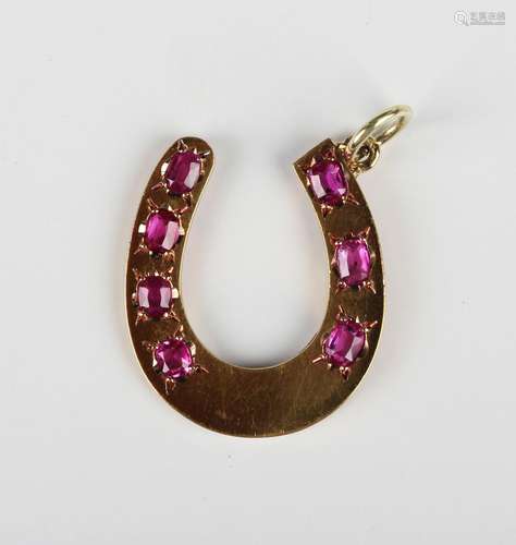 A gold and ruby pendant in the form of a horseshoe