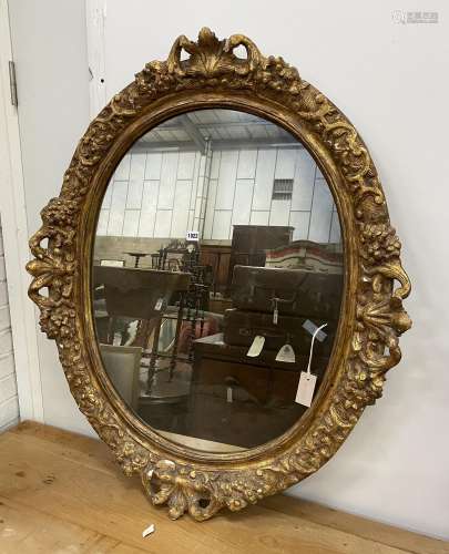 An oval giltwood and gesso wall mirror, width 89cm, height 1...