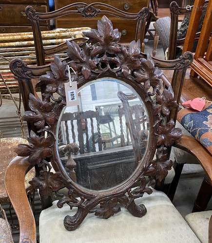 A 19th century oval Black Forest carved walnut wall mirror, ...