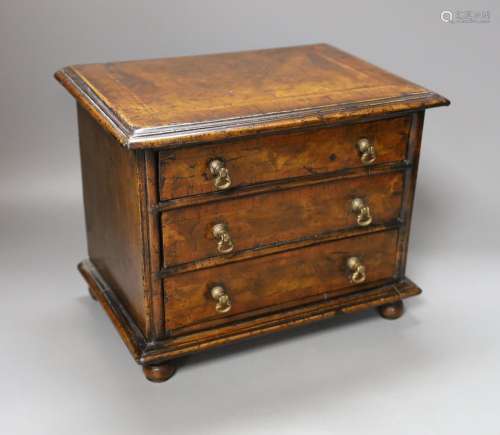 A cross banded walnut miniature chest of three drawers, 26cm...