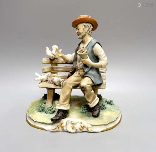 A Capodimonte figure of a tramp sat on a bench feeding doves...