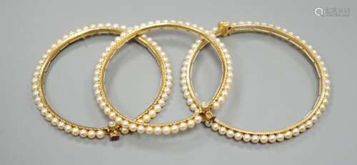 Three gilt white metal and cultured pearl set bangles.