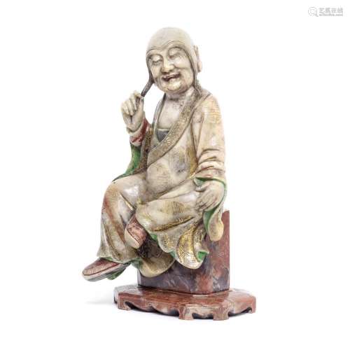 A PAINTED AND GILT SOAPSTONE MODEL OF A SEATED LUOHAN 17th/1...
