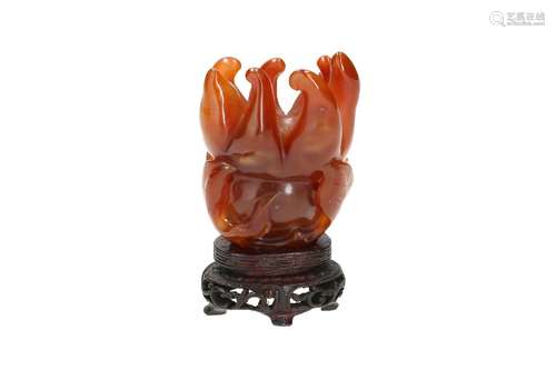 A carved carnelian sculpture on wooden base, depicting Buddh...