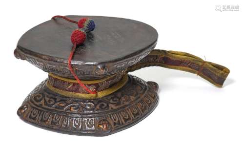 A WOODEN DAMARU.Tibet, 19th/20th c. Ø 13 cm.With silk case.