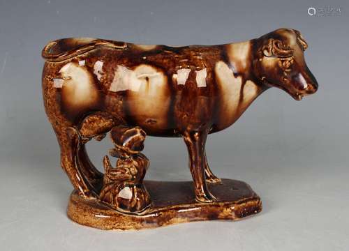 A Staffordshire pottery treacle glazed cow creamer and milkm...