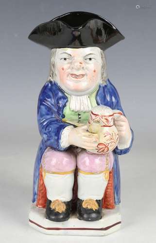 A pearlware Toby jug, circa 1820, modelled seated with a war...