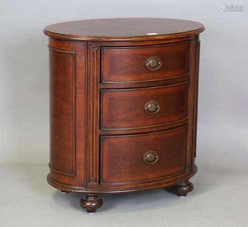 A modern reproduction mahogany oval chest of three drawers, ...