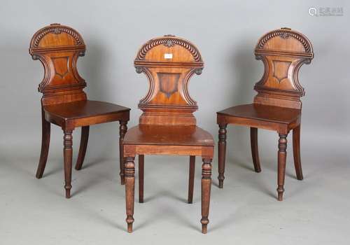 A set of three Regency mahogany hall chairs with finely carv...