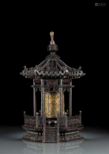 A GILT-BRONZE PRAYER WHEEL MOUNTED IN A CARVED WOOD PAGODA-S...