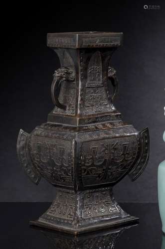 A SQUARE BRONZE VASE WITH LION HEAD HANDLES AND ARCHAIC DECO...