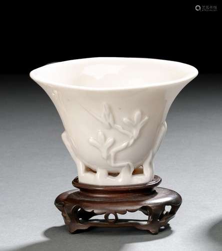 A SMALL DEHUA PRUNUS LIBATION CUP ON CARVED WOOD STAND