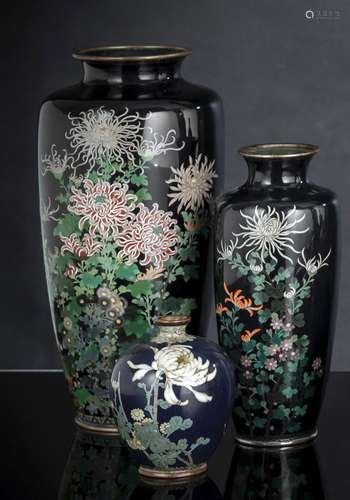 A GROUP OF THREE CLOISONNÉ ENAMEL FLOWER VASES ON DARK BLUE ...