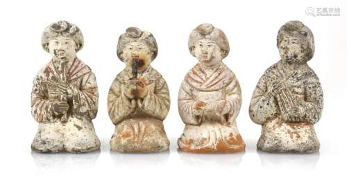 A SET OF FOUR PAINTED POTTERY FIGURES OF LADIES PLAYING DIFF...