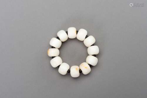 A WHITE AND RUSSET JADE BRACELET, 20th CENTURY